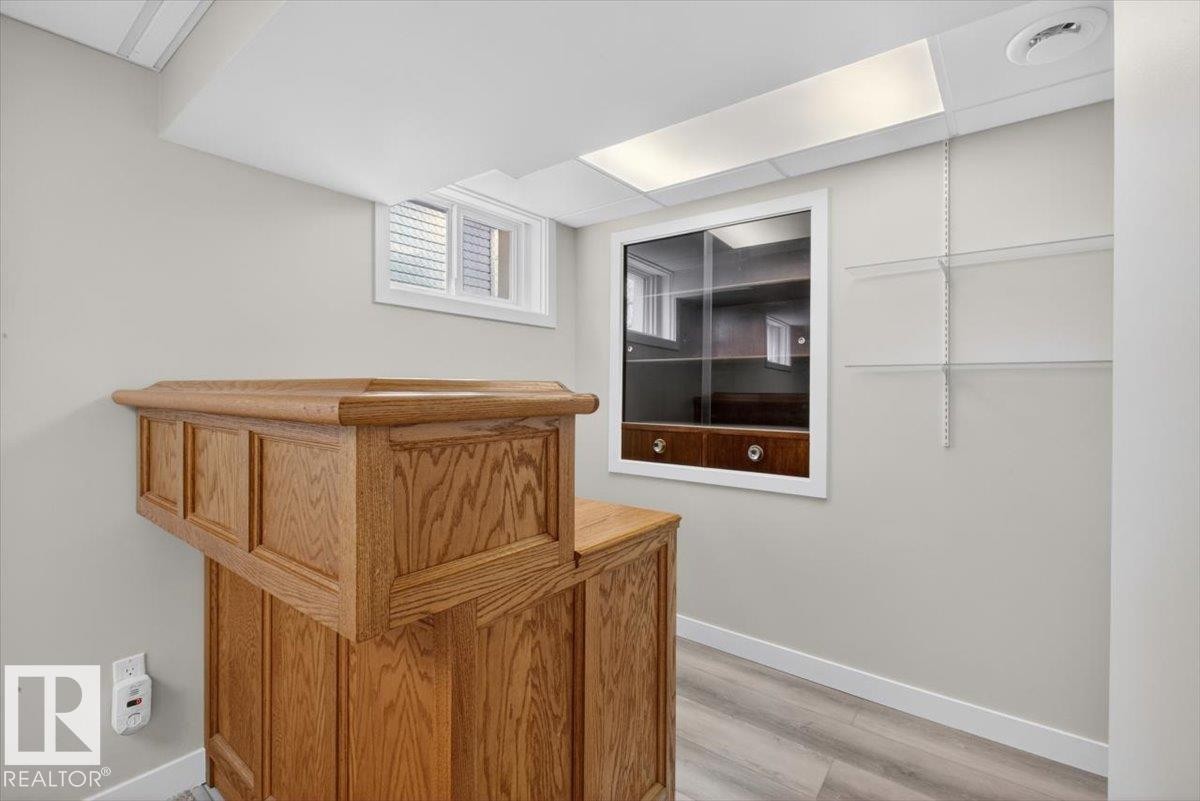 Wood-finish bar structure with panel detailing, complemented by a recessed wall display cabinet featuring glass doors and lower drawers - 9723 65 Avenue Nw, Edmonton, AB