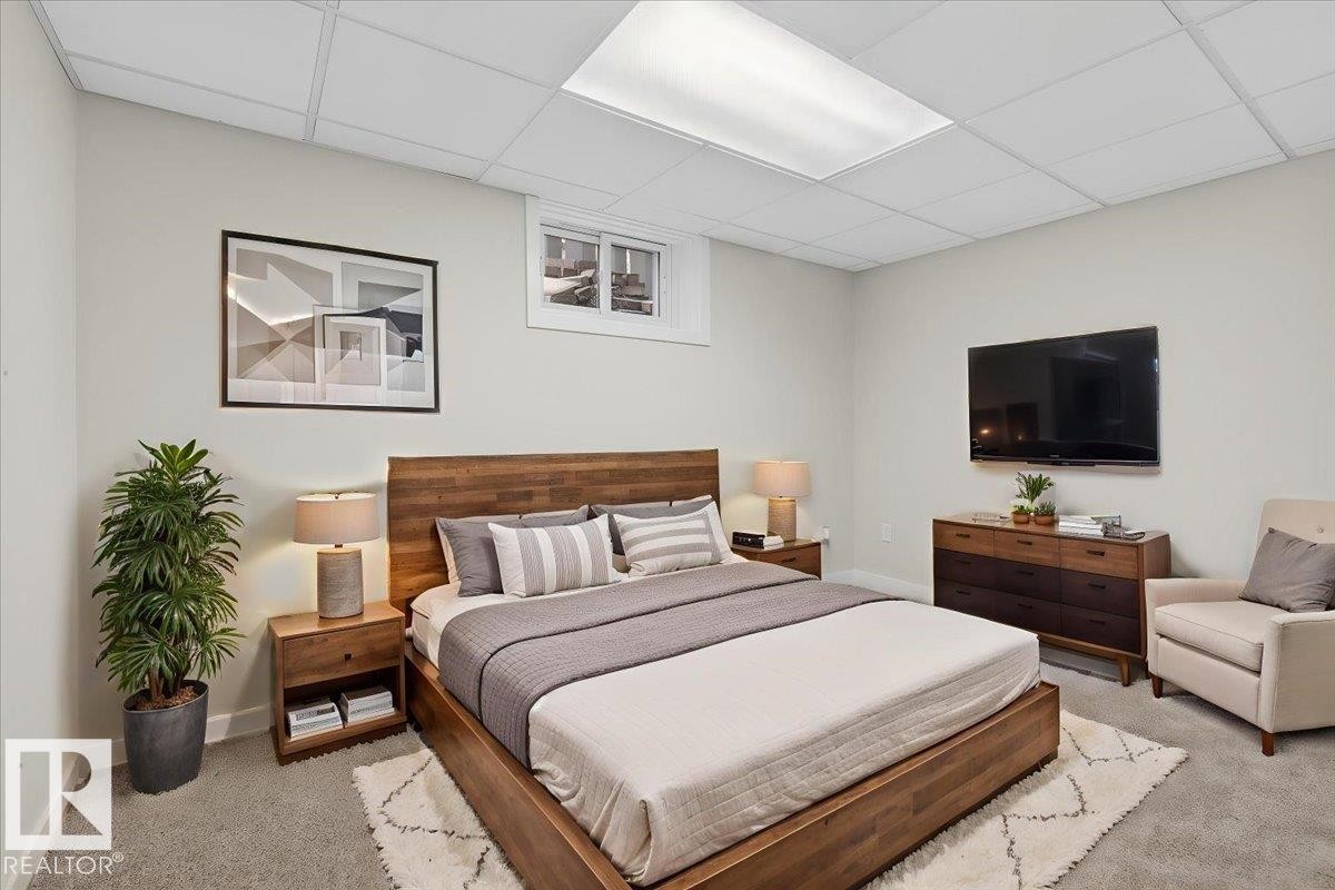 Bedroom featuring wood-finish flooring, a contemporary drop ceiling with integrated lighting, and a window providing natural light - 9723 65 Avenue Nw, Edmonton, AB