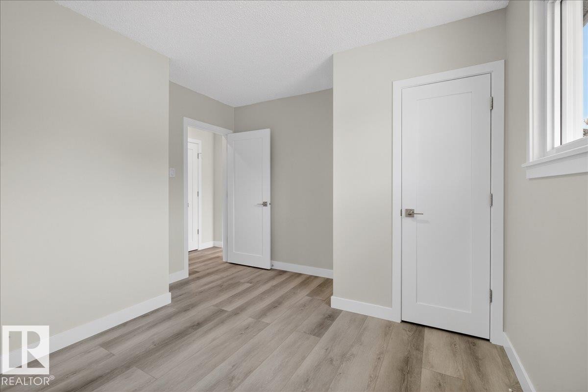 Room featuring light wood-finish flooring, light grey painted walls, white trim, and a white single-pane window - 9723 65 Avenue Nw, Edmonton, AB
