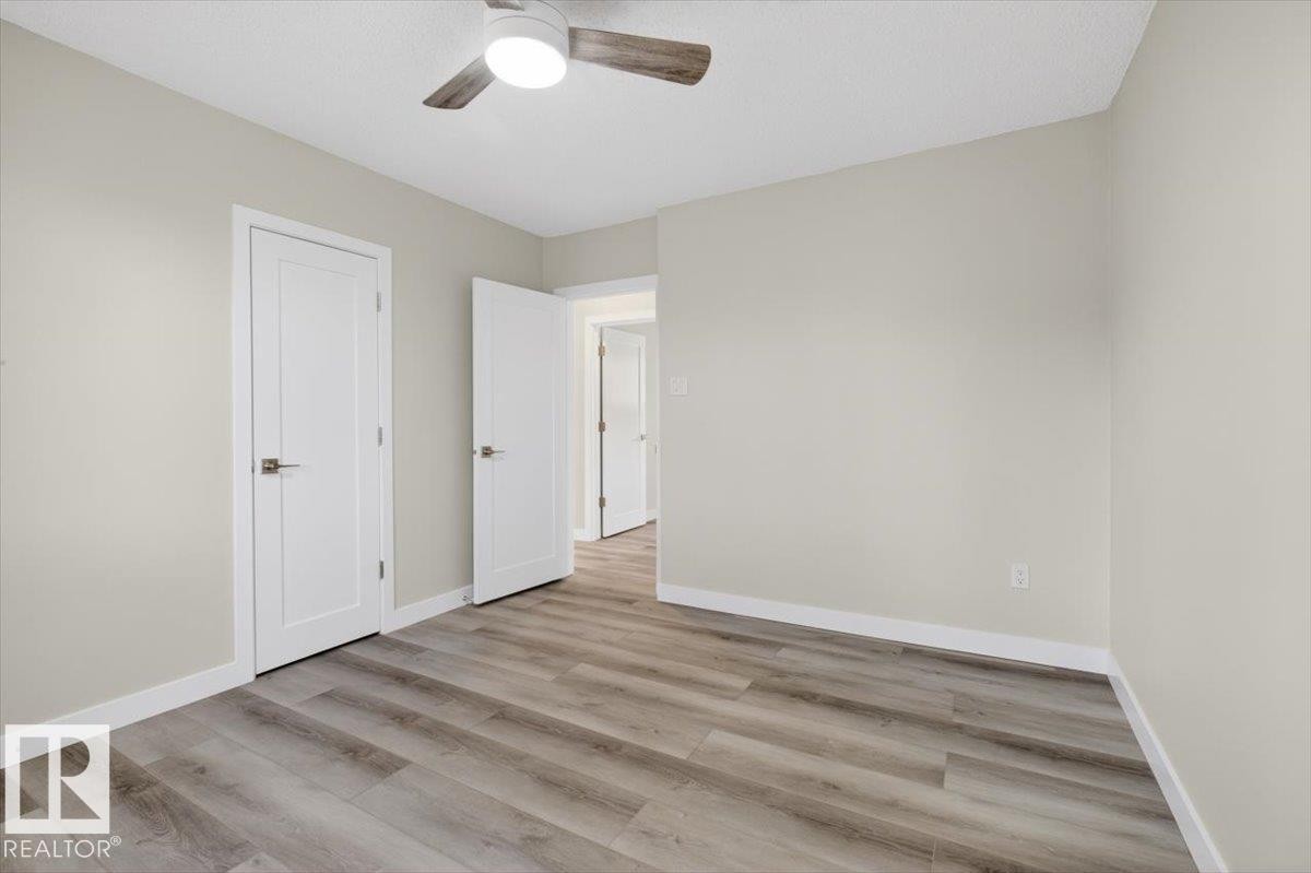 Room featuring wood-finish flooring, light-toned wall paint, white trim, and a ceiling fan with integrated lighting - 9723 65 Avenue Nw, Edmonton, AB