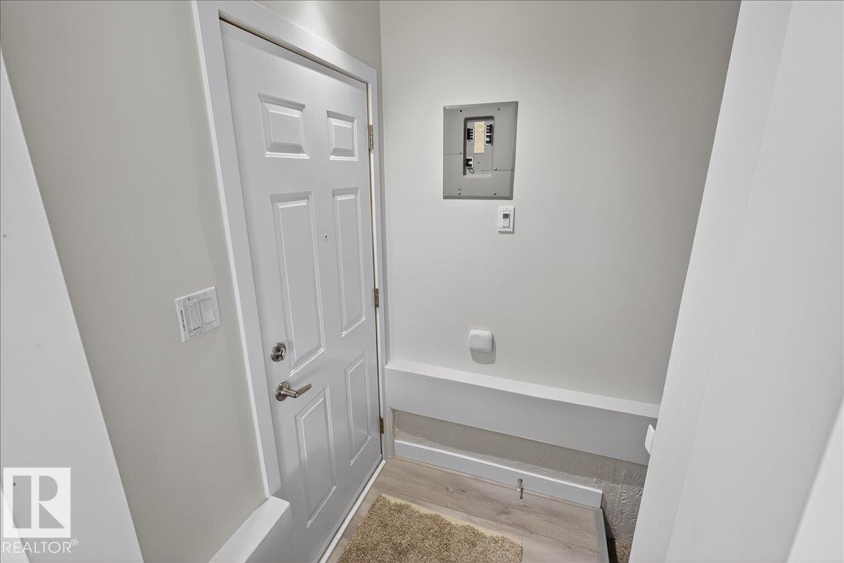 Entryway featuring a paneled door with brushed nickel hardware, wood-finish flooring, and a white electrical panel - 9723 65 Avenue Nw, Edmonton, AB