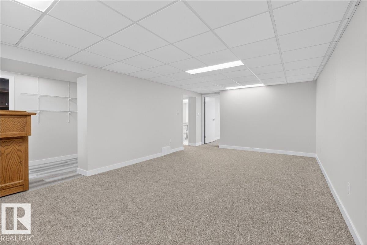 Carpeted room featuring a drop ceiling with recessed lighting - 9723 65 Avenue Nw, Edmonton, AB
