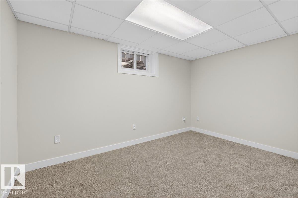 Room with light-colored walls, neutral carpet flooring, a drop ceiling, and a single window with white trim - 9723 65 Avenue Nw, Edmonton, AB