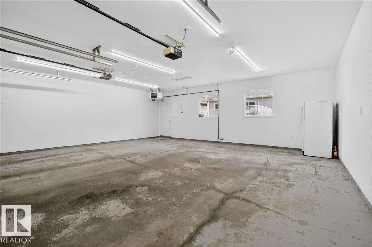 Spacious garage with white walls, multiple windows, and overhead fluorescent lighting - 9723 65 Avenue Nw, Edmonton, AB