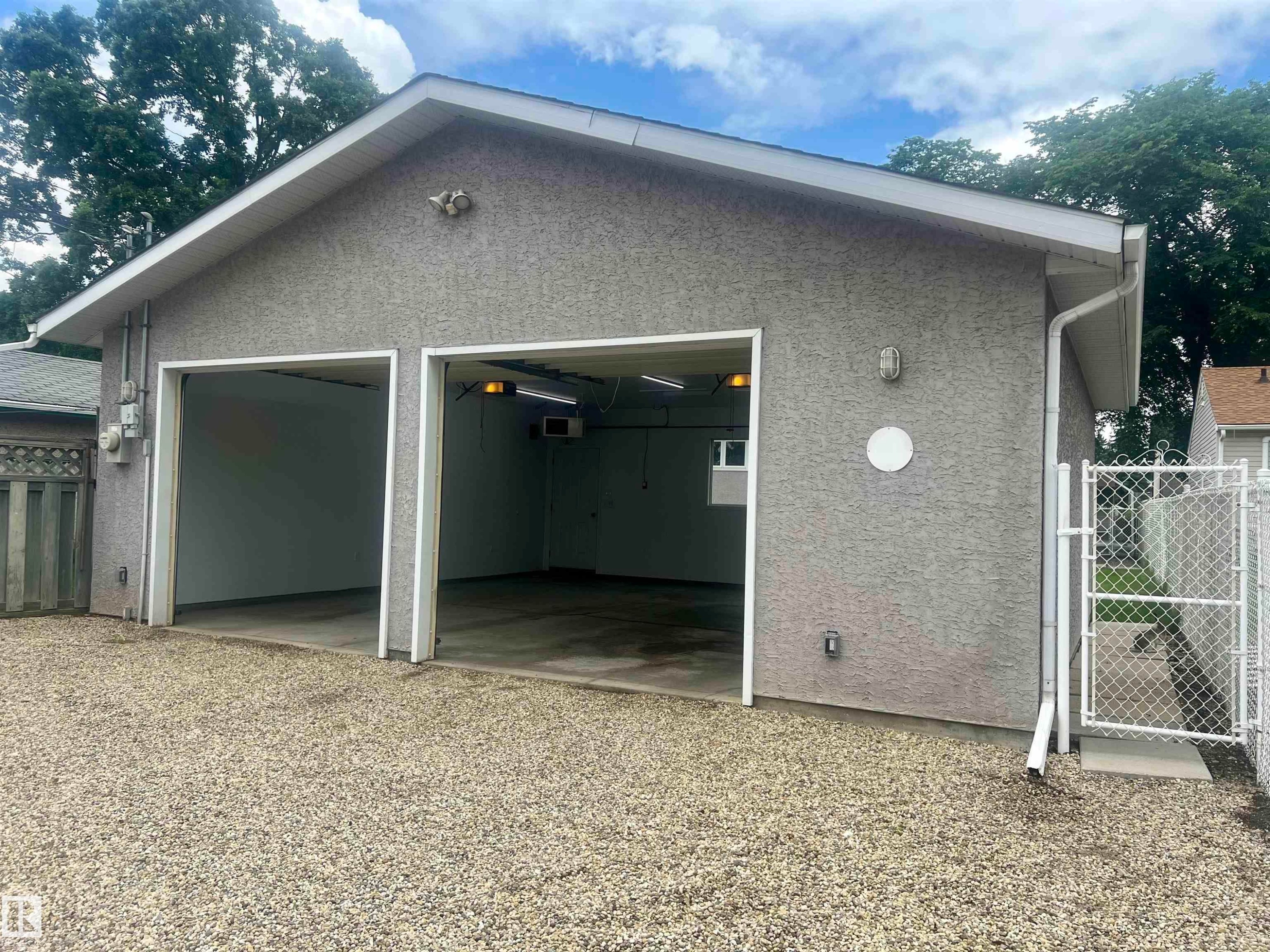 Two-car garage with a textured stucco exterior and a gravel driveway - 9723 65 Avenue Nw, Edmonton, AB