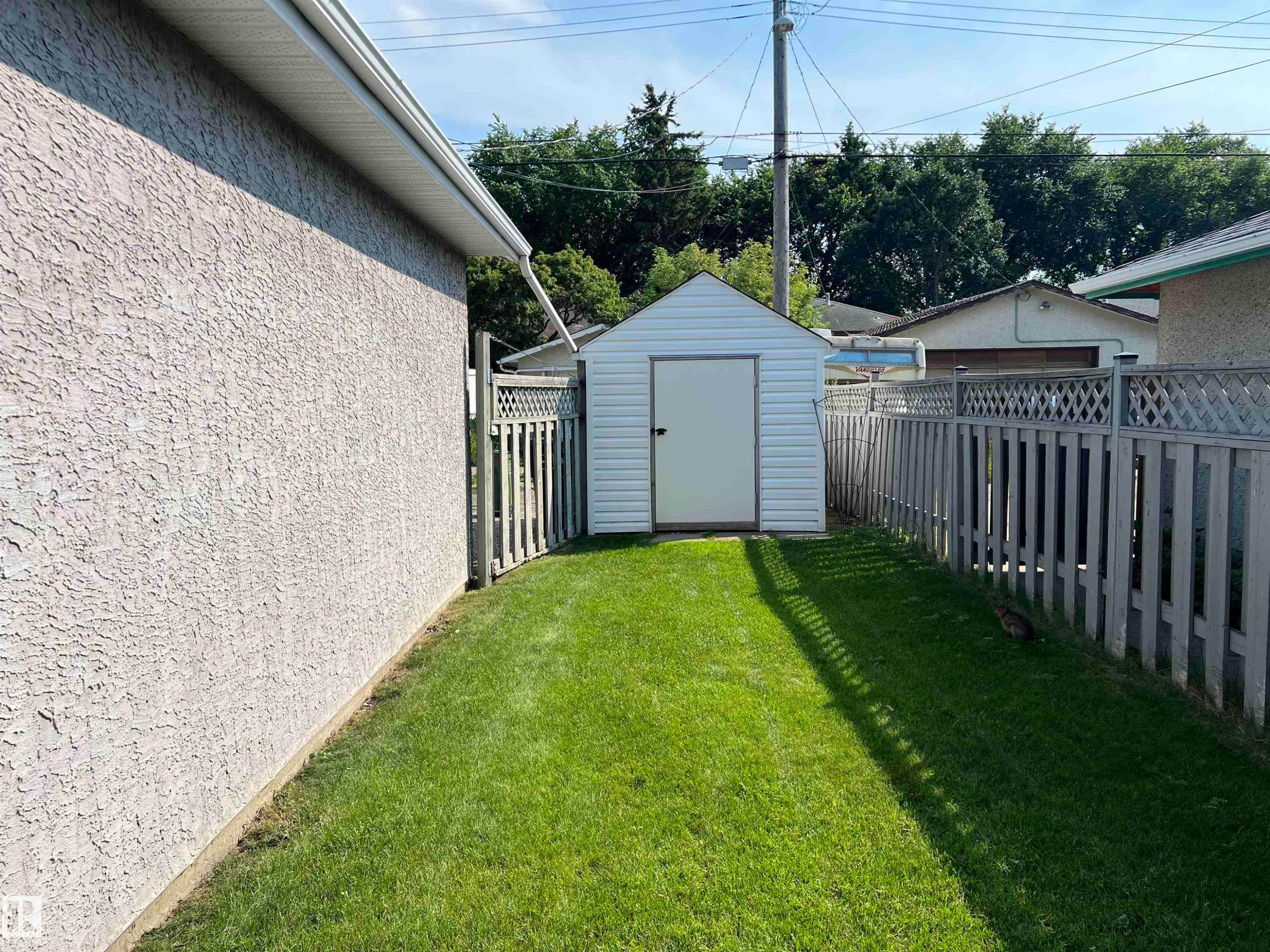 Manicured lawn area featuring a white vinyl-sided storage shed with a gable roof - 9723 65 Avenue Nw, Edmonton, AB