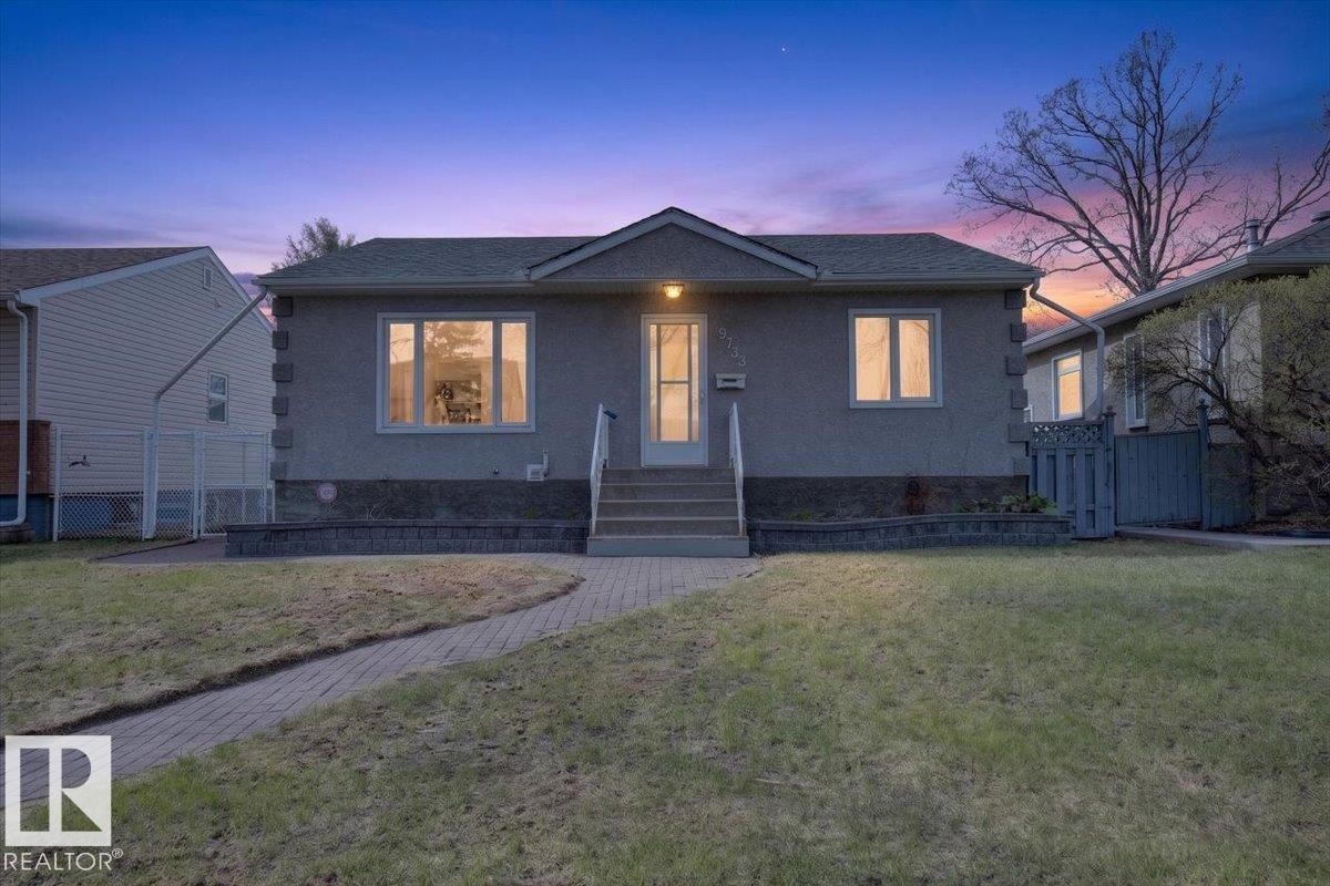 Front exterior featuring stucco siding, a gabled roof, and a stone-look foundation - 9723 65 Avenue Nw, Edmonton, AB