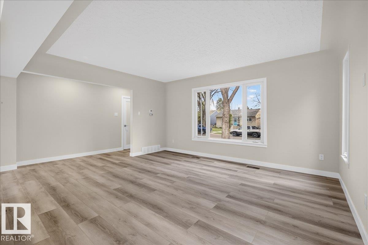 Spacious interior featuring wood-finish flooring, neutral wall tones, and recessed ceiling details - 9723 65 Avenue Nw, Edmonton, AB