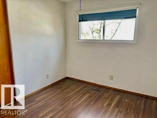 Room featuring wood-finish flooring, white painted walls, a standard window with blinds, and a wood-panel closet door - 5206 51Ave, Willingdon, AB - Indoor Photo Showing Other Room