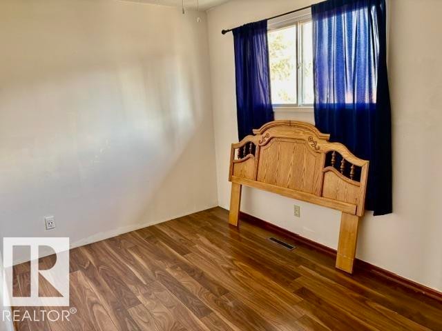Bright room featuring wood-finish flooring, a window with a dark curtain rod, white walls, and white trim - 5206 51Ave, Willingdon, AB - Indoor Photo Showing Other Room