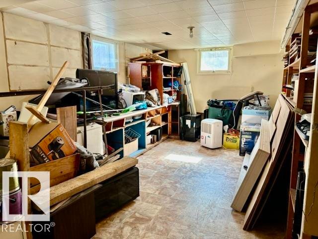 Basement space featuring vinyl flooring, multiple windows, built-in shelving, and a drop ceiling - 5206 51Ave, Willingdon, AB - Indoor