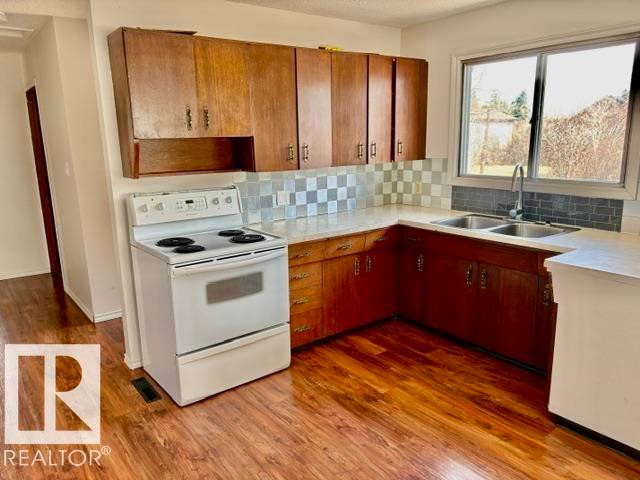 Kitchen featuring wood-finish flooring and ample cabinetry - 5206 51Ave, Willingdon, AB - Indoor Photo Showing Kitchen With Double Sink