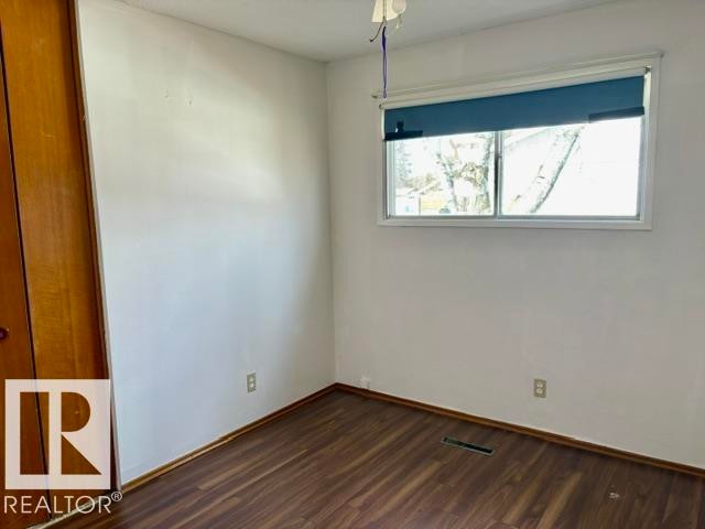 Room featuring wood-finish flooring, a double-pane window, and a built-in closet with wood doors - 5206 51Ave, Willingdon, AB - Indoor Photo Showing Other Room
