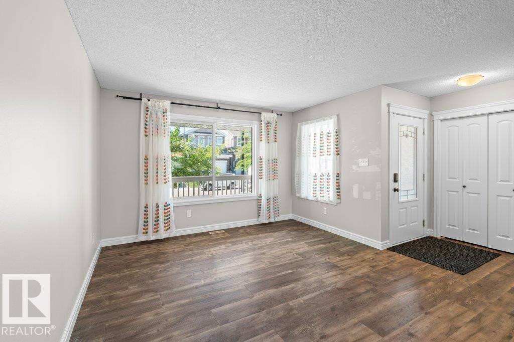 Spacious entry area featuring durable wood-finish flooring, a large picture window, and a frosted glass-paneled entry door - 1627 167 Street Sw, Edmonton, AB - Indoor Photo Showing Other Room