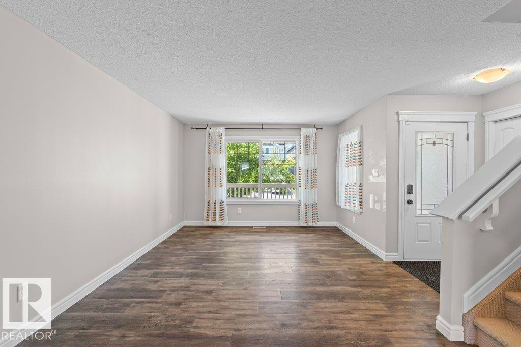 Spacious room featuring wood-finish flooring, light grey walls, and a large window with white trim - 1627 167 Street Sw, Edmonton, AB - Indoor Photo Showing Other Room