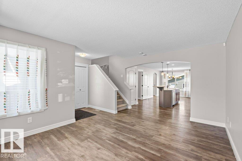 Spacious main living area featuring wood-finish flooring, light grey wall tones, and white trim - 1627 167 Street Sw, Edmonton, AB - Indoor
