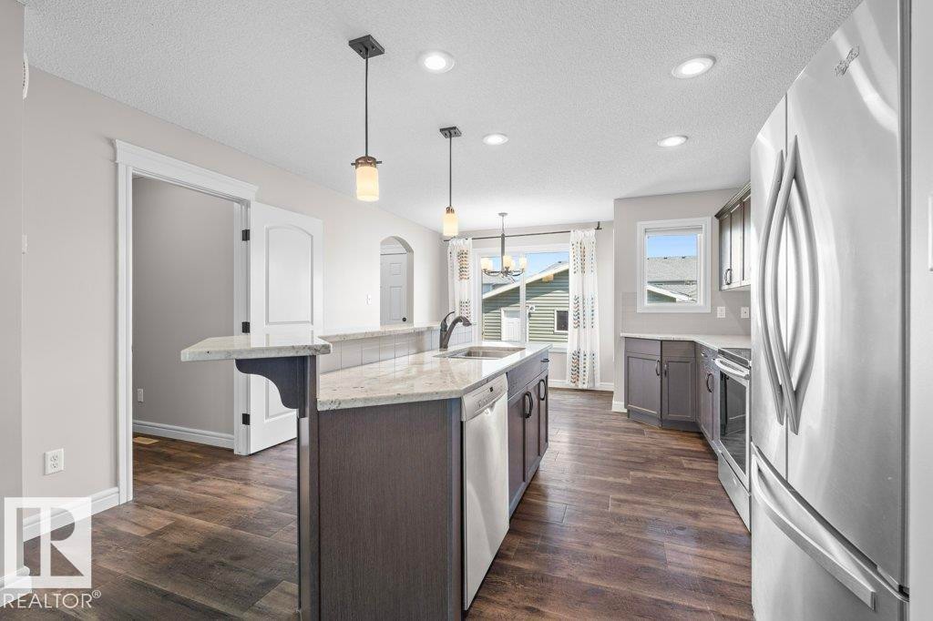 Modern kitchen featuring wood-finish flooring, recessed lighting, and stainless steel appliances - 1627 167 Street Sw, Edmonton, AB - Indoor Photo Showing Kitchen With Upgraded Kitchen