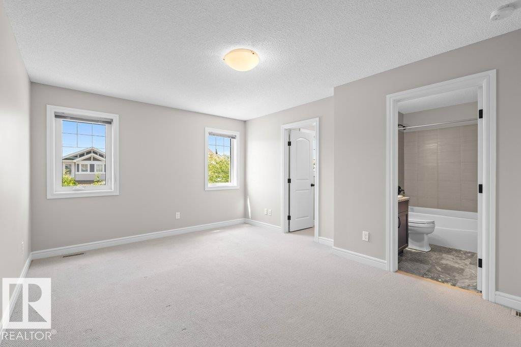 Spacious room with light-toned carpeting, two windows, and a flush-mount ceiling light - 1627 167 Street Sw, Edmonton, AB - Indoor Photo Showing Other Room