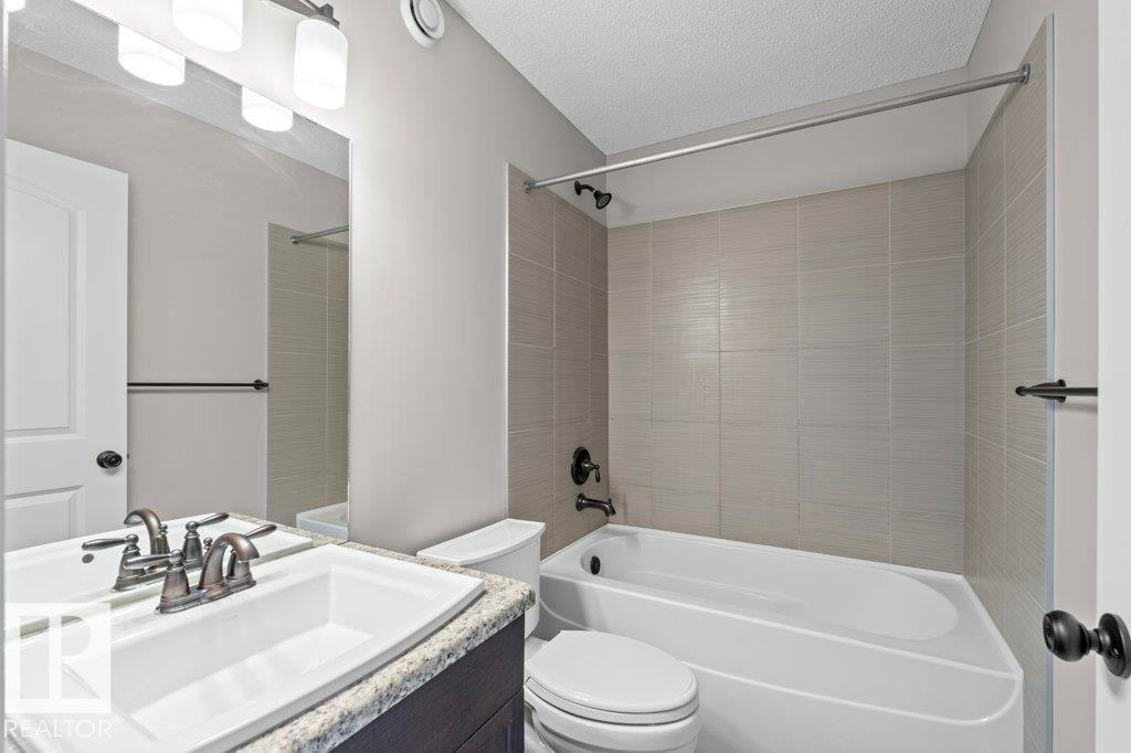 Bathroom featuring a vanity with granite-style countertop, white undermount sink, and brushed nickel faucet - 1627 167 Street Sw, Edmonton, AB - Indoor Photo Showing Bathroom