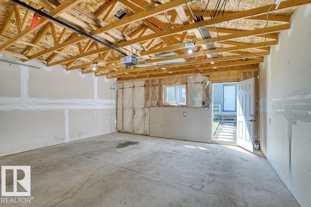 Spacious unfinished garage featuring concrete flooring and exposed ceiling trusses - 1627 167 Street Sw, Edmonton, AB - Indoor
