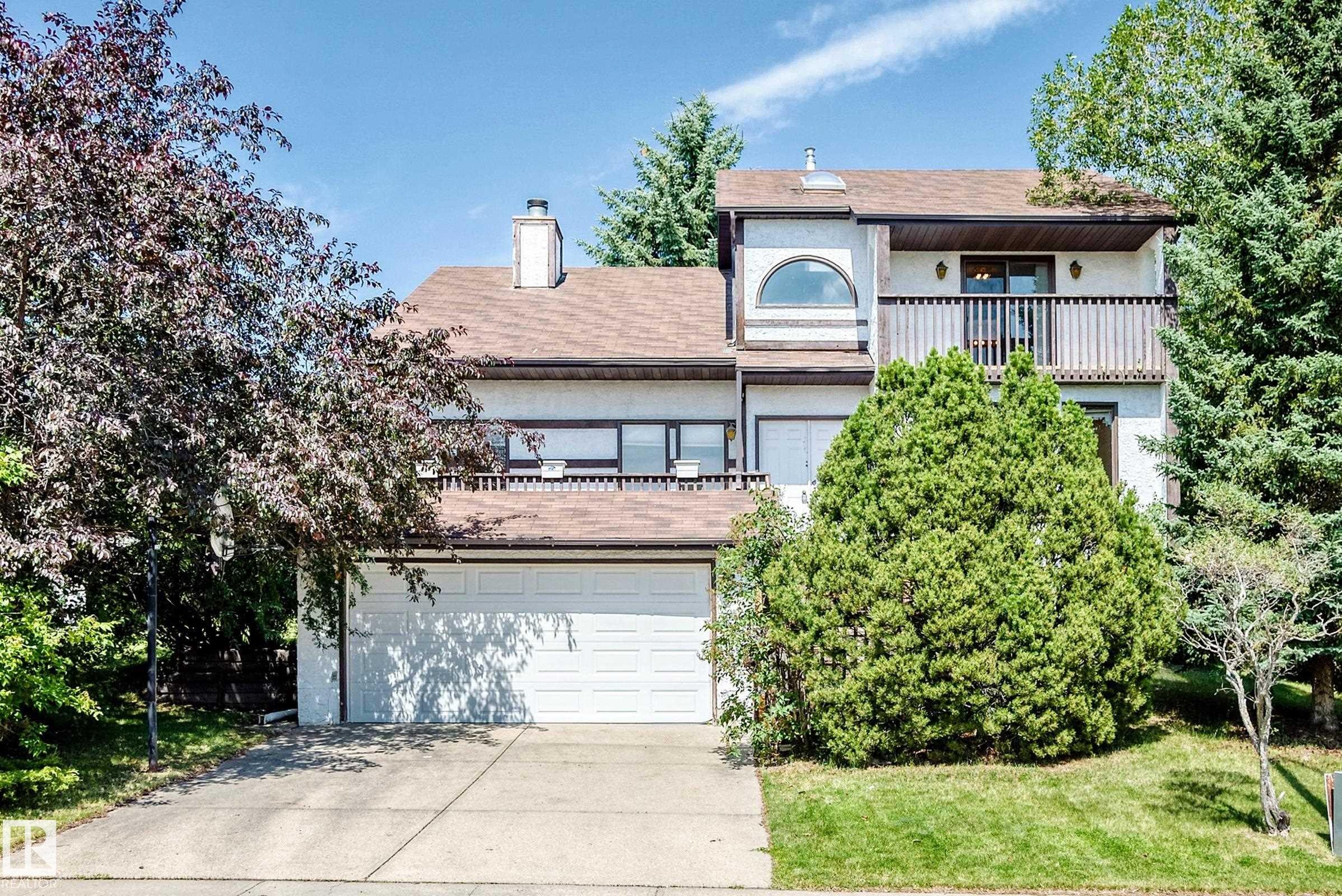 Multi-level residence featuring a two-car garage, upper-level balcony with wood railing, and an arched window - 4208 Ramsay Road Nw, Edmonton, AB - Outdoor