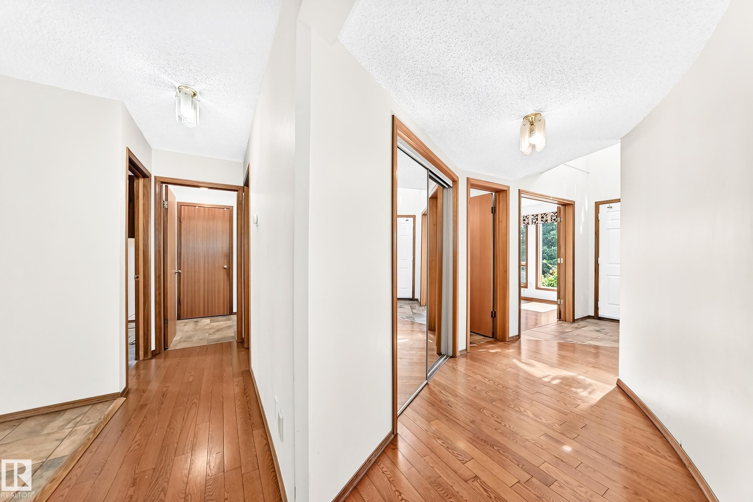 Hallway featuring wood-finish flooring, white walls, and wood-trim doorways - 4208 Ramsay Road Nw, Edmonton, AB - Indoor Photo Showing Other Room
