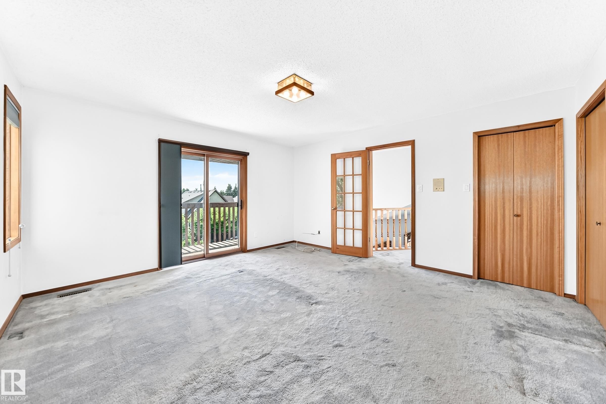 Spacious room featuring light gray carpeting, crisp white walls, and warm wood trim - 4208 Ramsay Road Nw, Edmonton, AB - Indoor Photo Showing Other Room