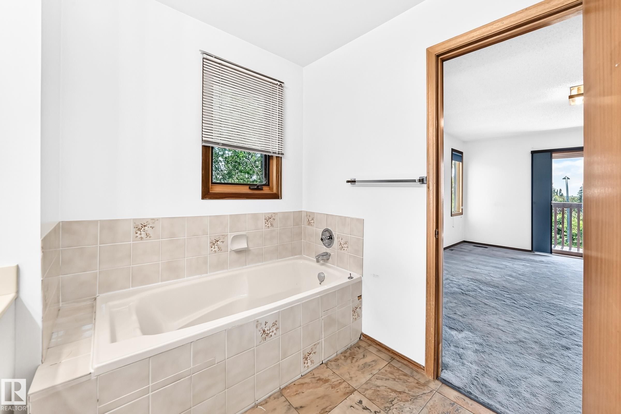 Soaking tub with tiled surround and integrated window - 4208 Ramsay Road Nw, Edmonton, AB - Indoor Photo Showing Bathroom