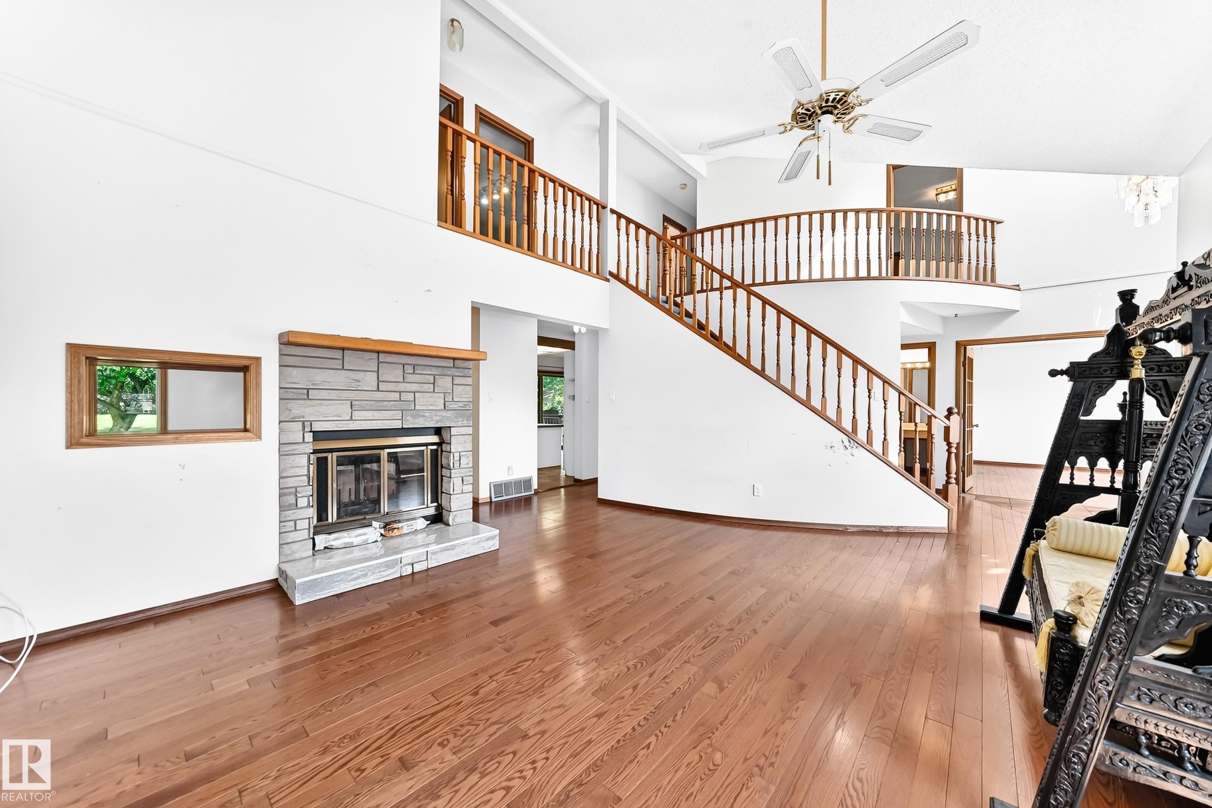 Spacious main living area featuring wood-finish flooring, a stone-front fireplace with a wood mantle, and a built-in window - 4208 Ramsay Road Nw, Edmonton, AB - Indoor With Fireplace