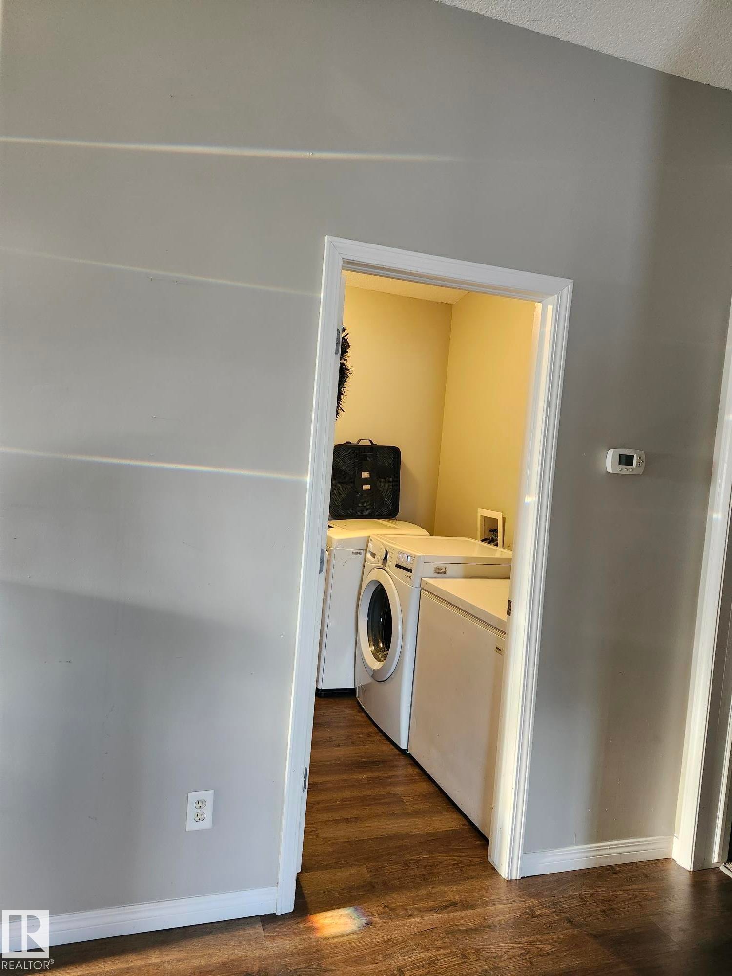 Dedicated laundry area featuring wood-finish flooring, white trim, and light-toned walls - 5273 50 Street, Mayerthorpe, AB - Indoor Photo Showing Laundry Room