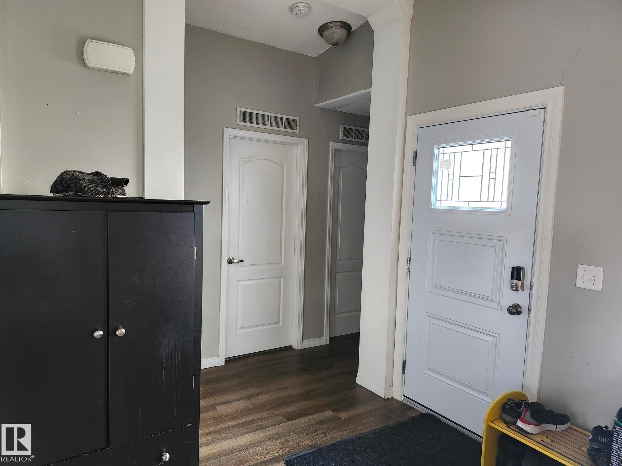 Entryway featuring wood-finish flooring, a paneled door with decorative glass inserts, and a smart lock - 5273 50 Street, Mayerthorpe, AB - Indoor Photo Showing Other Room