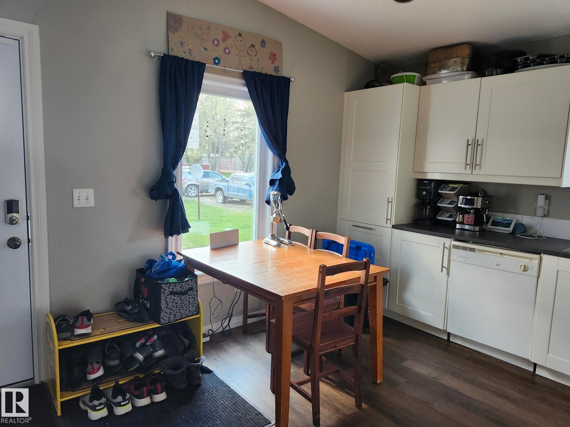 Kitchen area featuring white cabinetry, dark countertops, and wood-finish flooring - 5273 50 Street, Mayerthorpe, AB - Indoor Photo Showing Kitchen