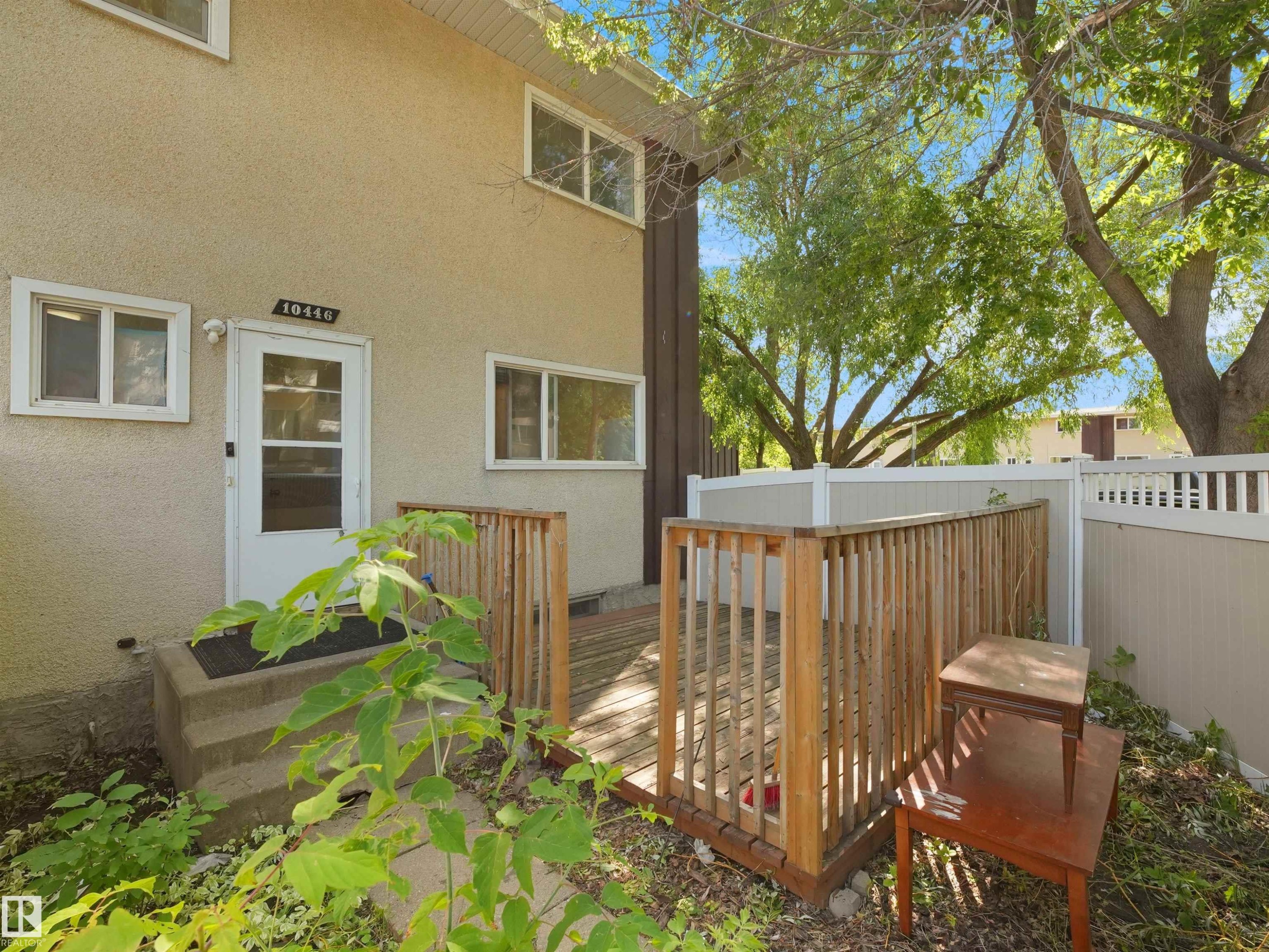 Stucco exterior with multiple windows and a private wooden deck - 10446 55 Avenue Nw, Edmonton, AB - Outdoor