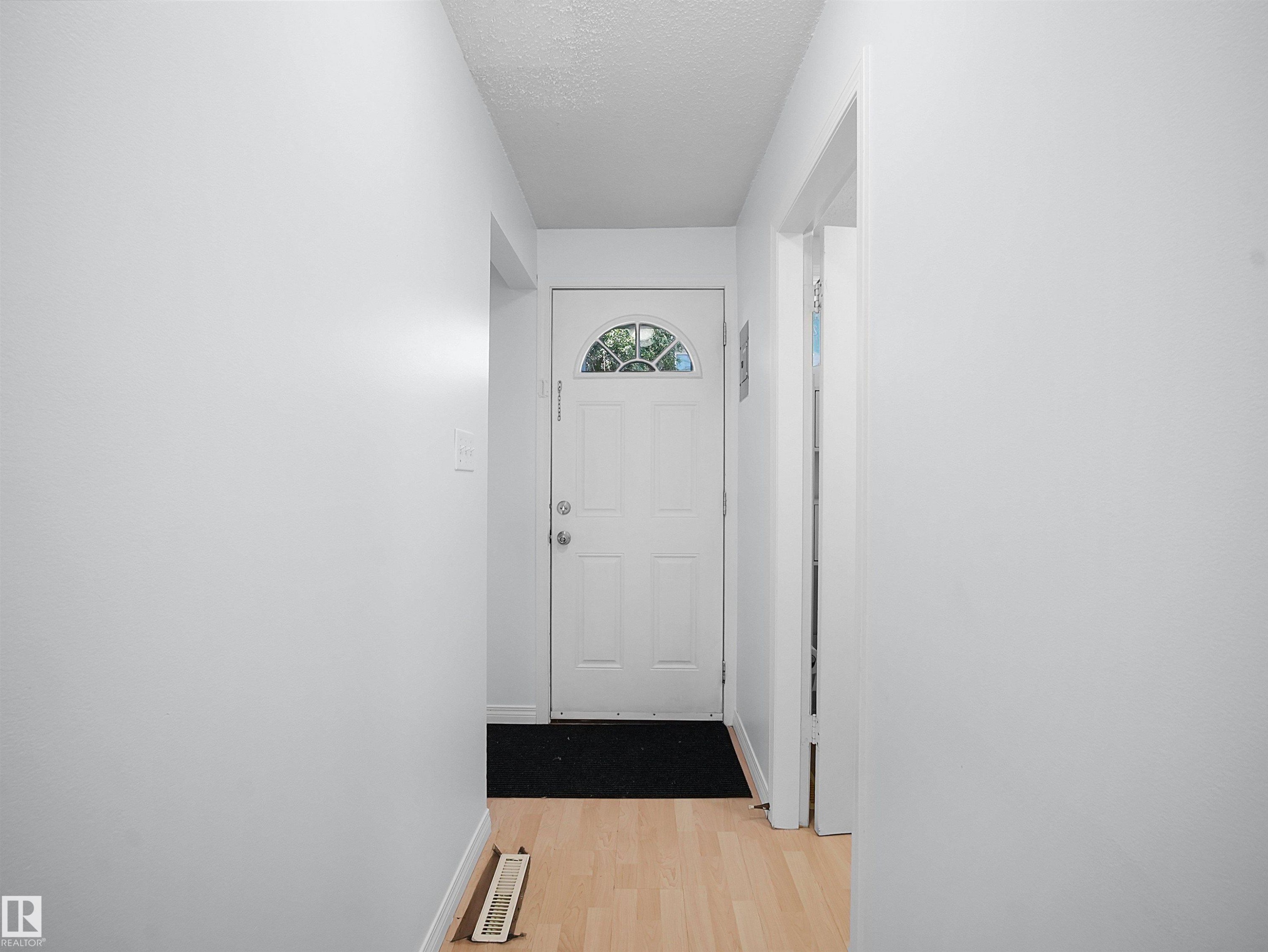 Entryway featuring light wood-finish flooring, white walls, and a white paneled door with an arched window insert - 10446 55 Avenue Nw, Edmonton, AB - Indoor Photo Showing Other Room