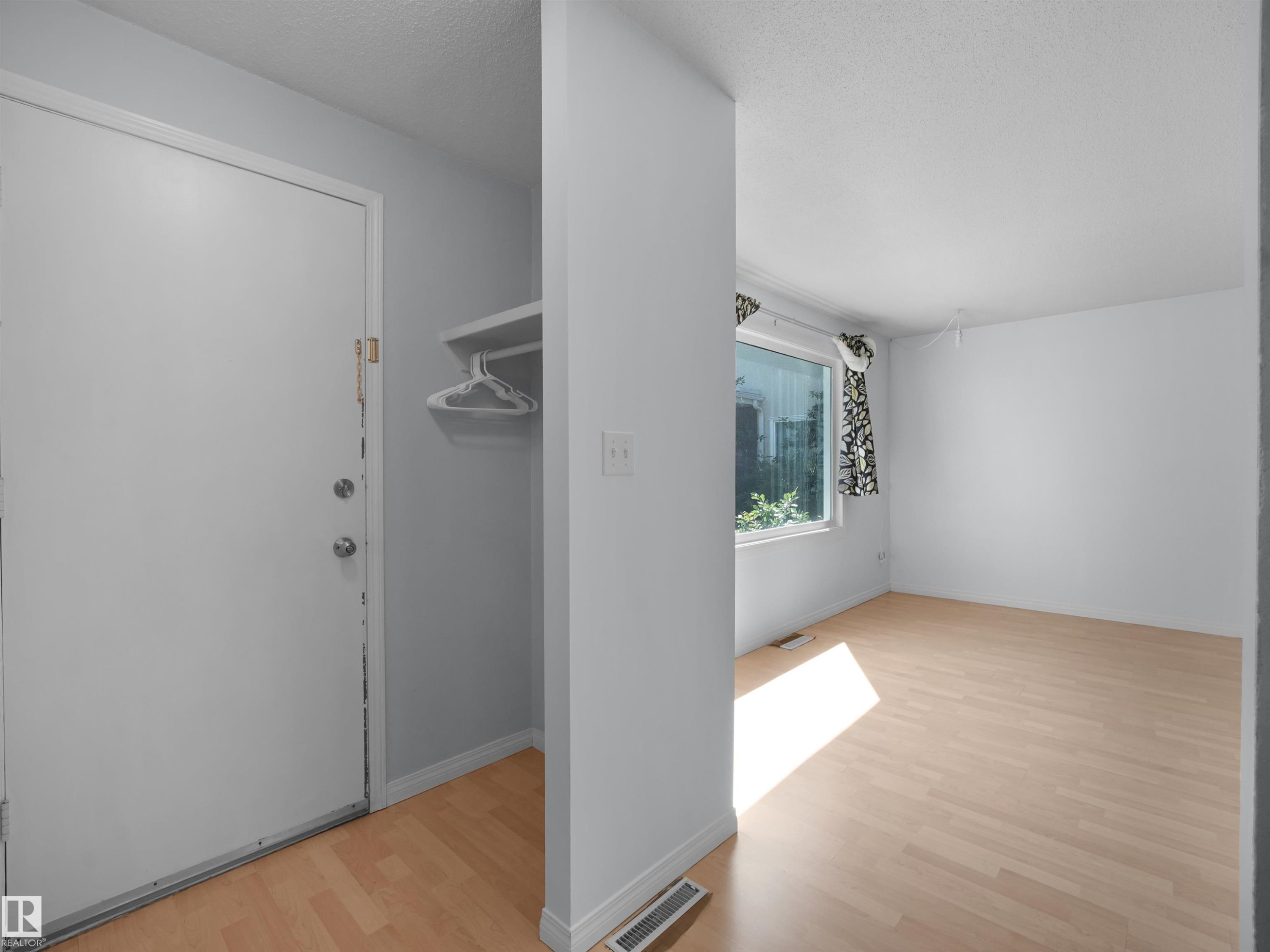 Entryway and room featuring wood-finish flooring, white walls, and a window with exterior views - 10446 55 Avenue Nw, Edmonton, AB - Indoor Photo Showing Other Room