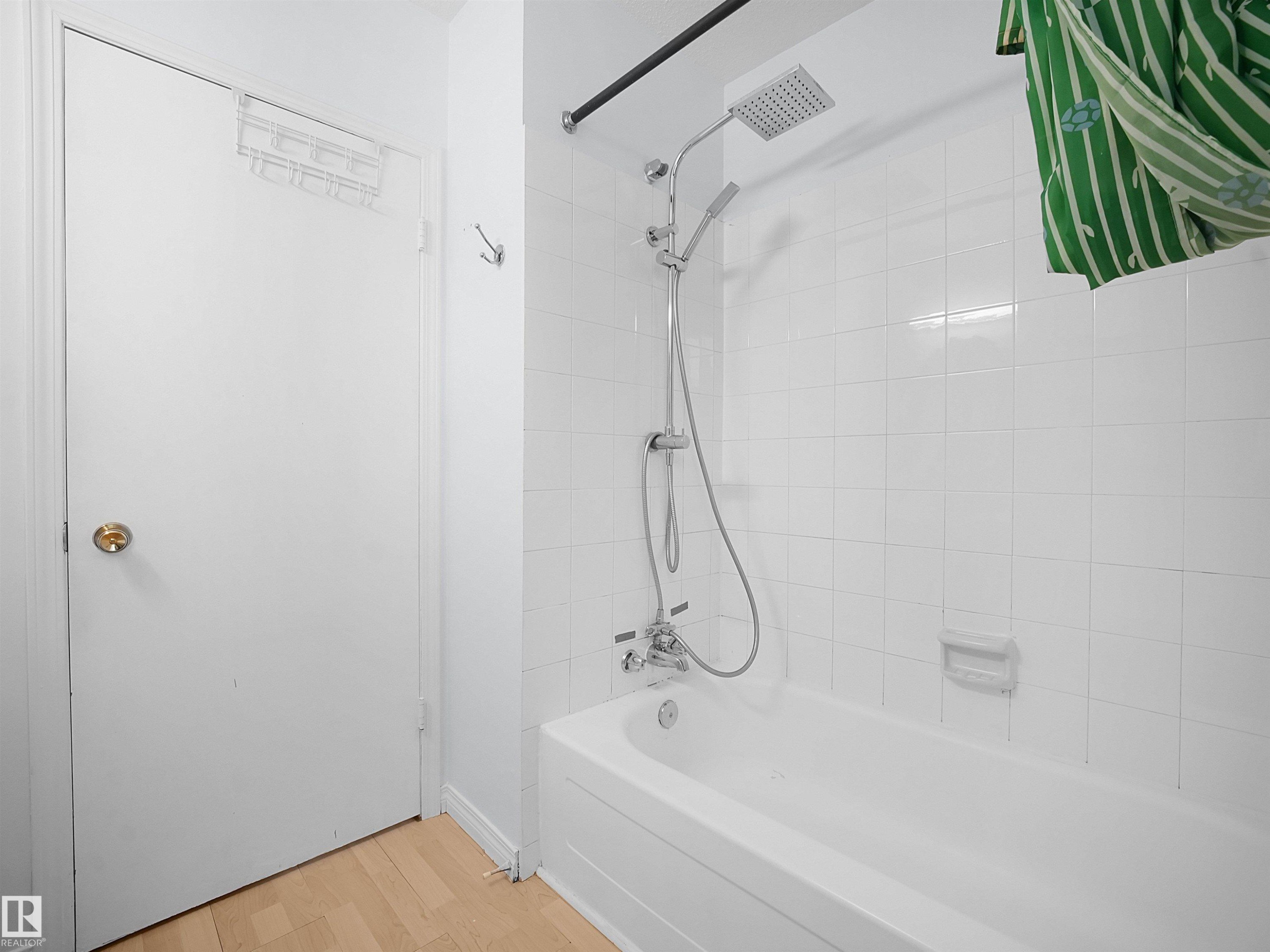 White tiled shower with a rainfall showerhead and handheld sprayer, featuring a built-in tub - 10446 55 Avenue Nw, Edmonton, AB - Indoor Photo Showing Bathroom