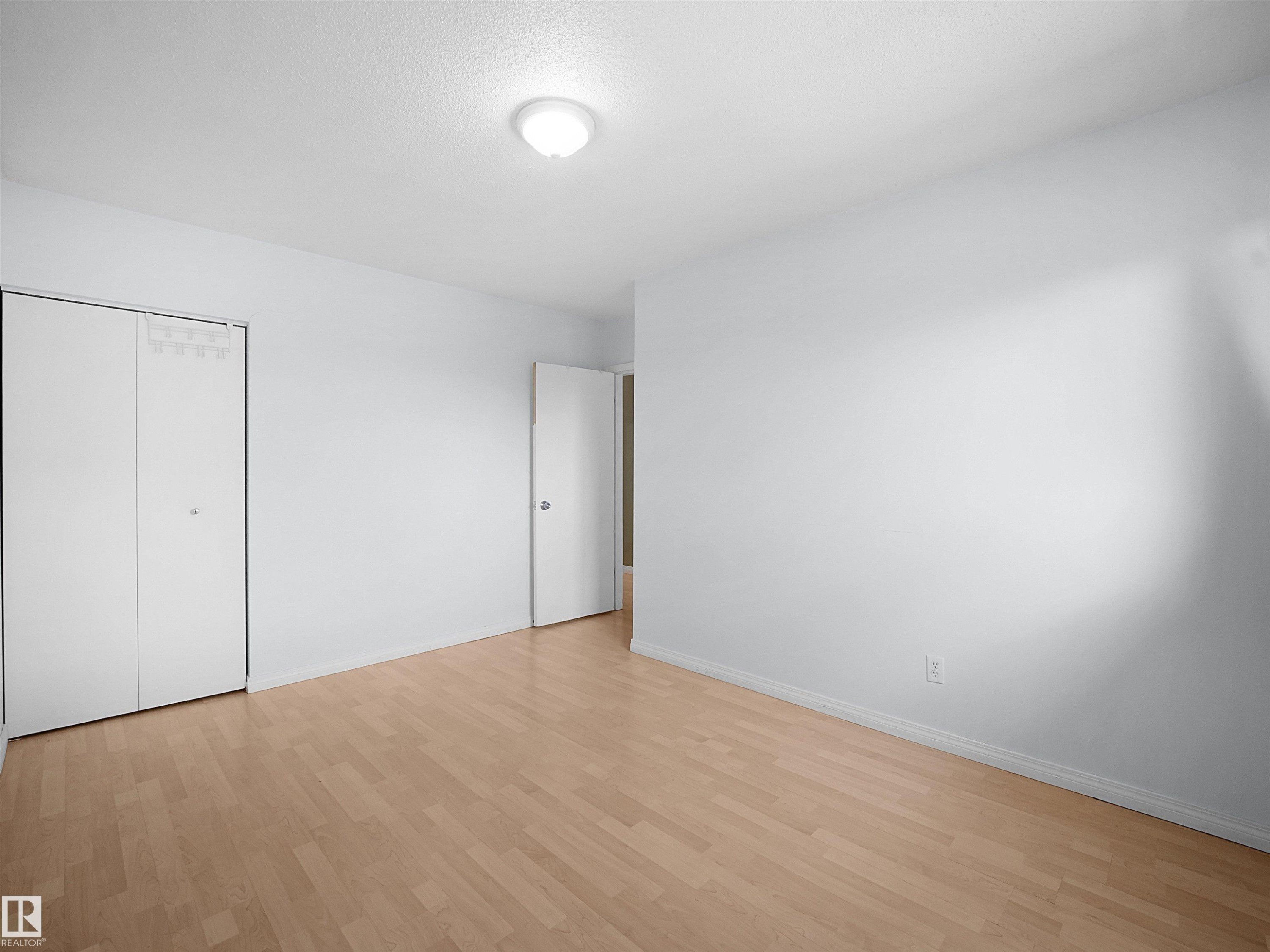 Light-toned wood-finish flooring complements the neutral wall color - 10446 55 Avenue Nw, Edmonton, AB - Indoor Photo Showing Other Room