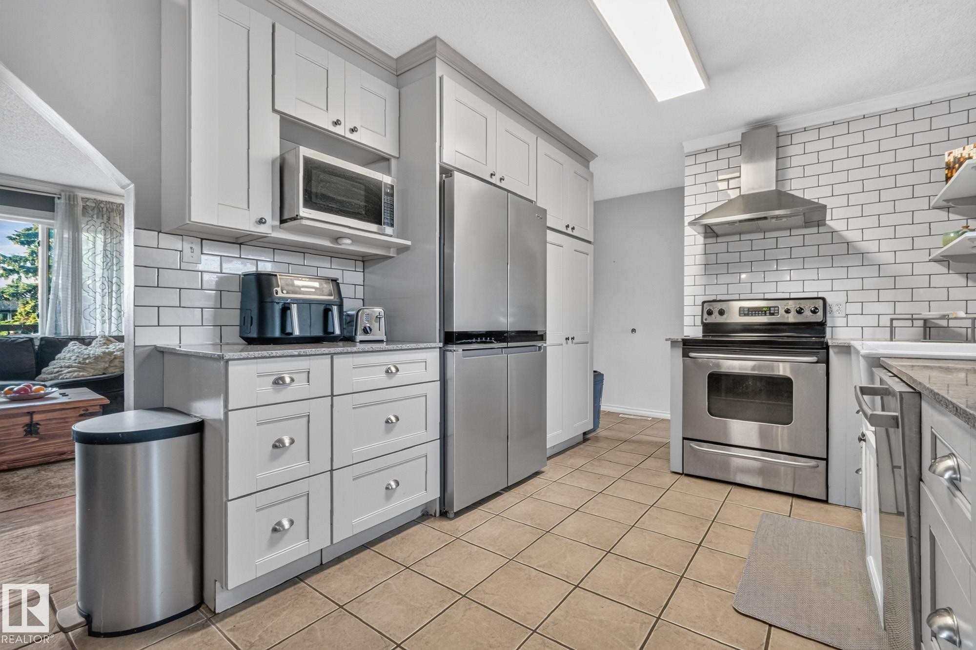 Kitchen featuring stainless steel appliances, grey shaker-style cabinetry, a white subway tile backsplash, and neutral tile flooring - 5307 104 Avenue Nw, Edmonton, AB - Indoor Photo Showing Kitchen With Upgraded Kitchen