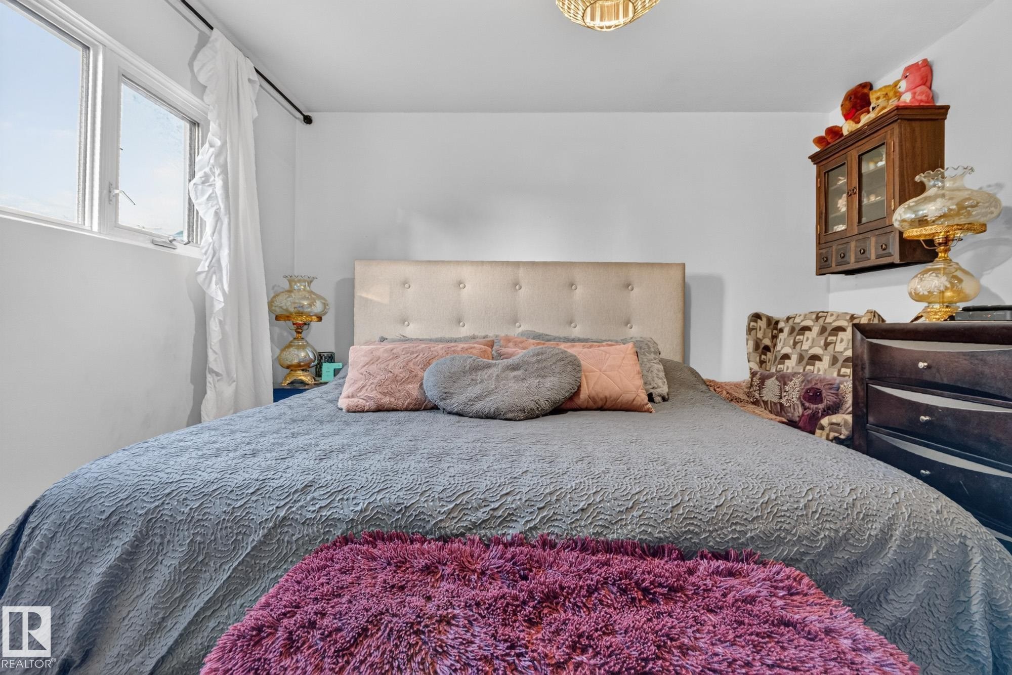 Room featuring an upholstered headboard, multiple windows with natural light, and a ceiling light fixture - 5307 104 Avenue Nw, Edmonton, AB - Indoor Photo Showing Bedroom