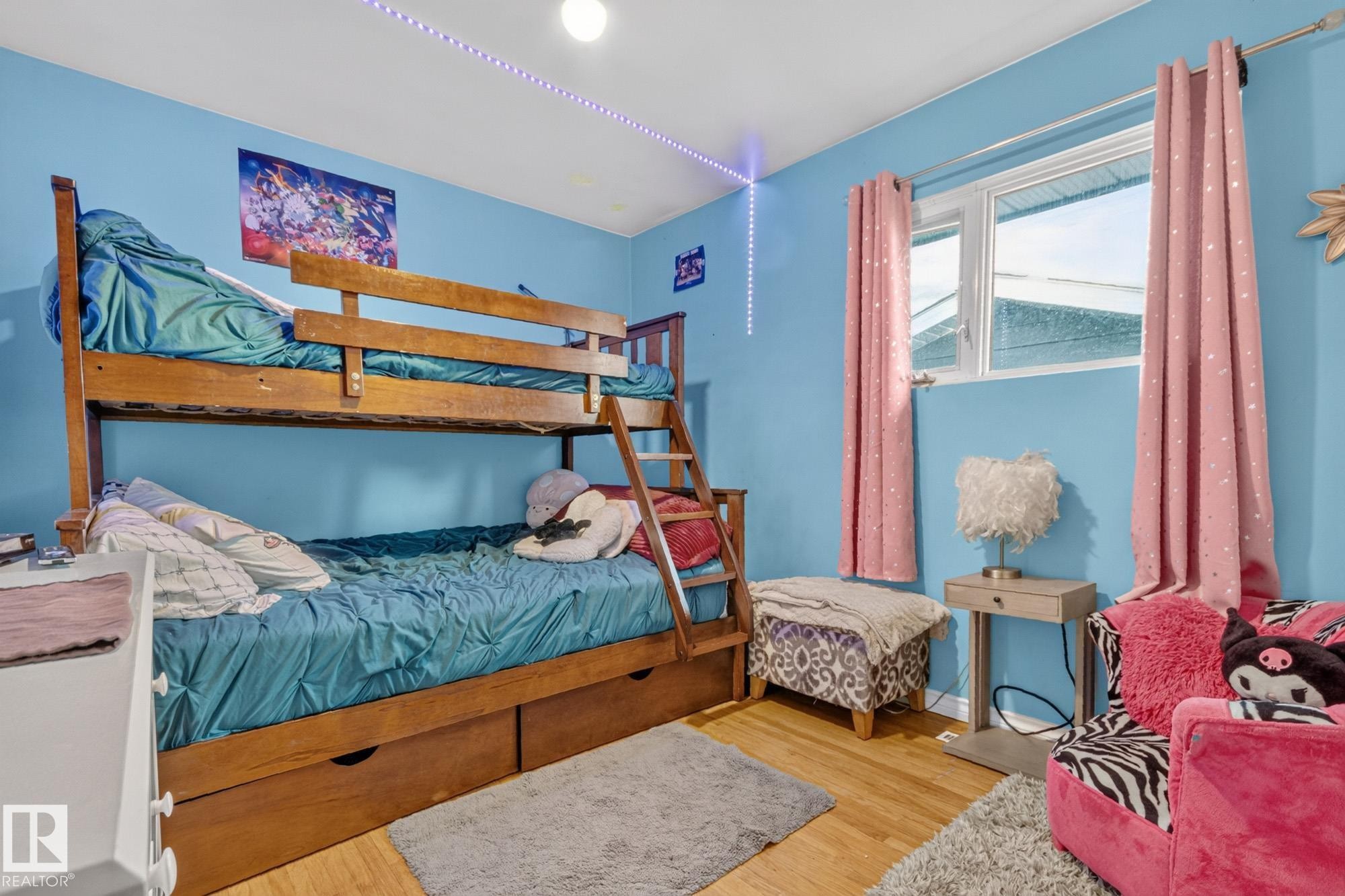 Light wood-finish flooring complements the bright wall color in this room - 5307 104 Avenue Nw, Edmonton, AB - Indoor Photo Showing Bedroom