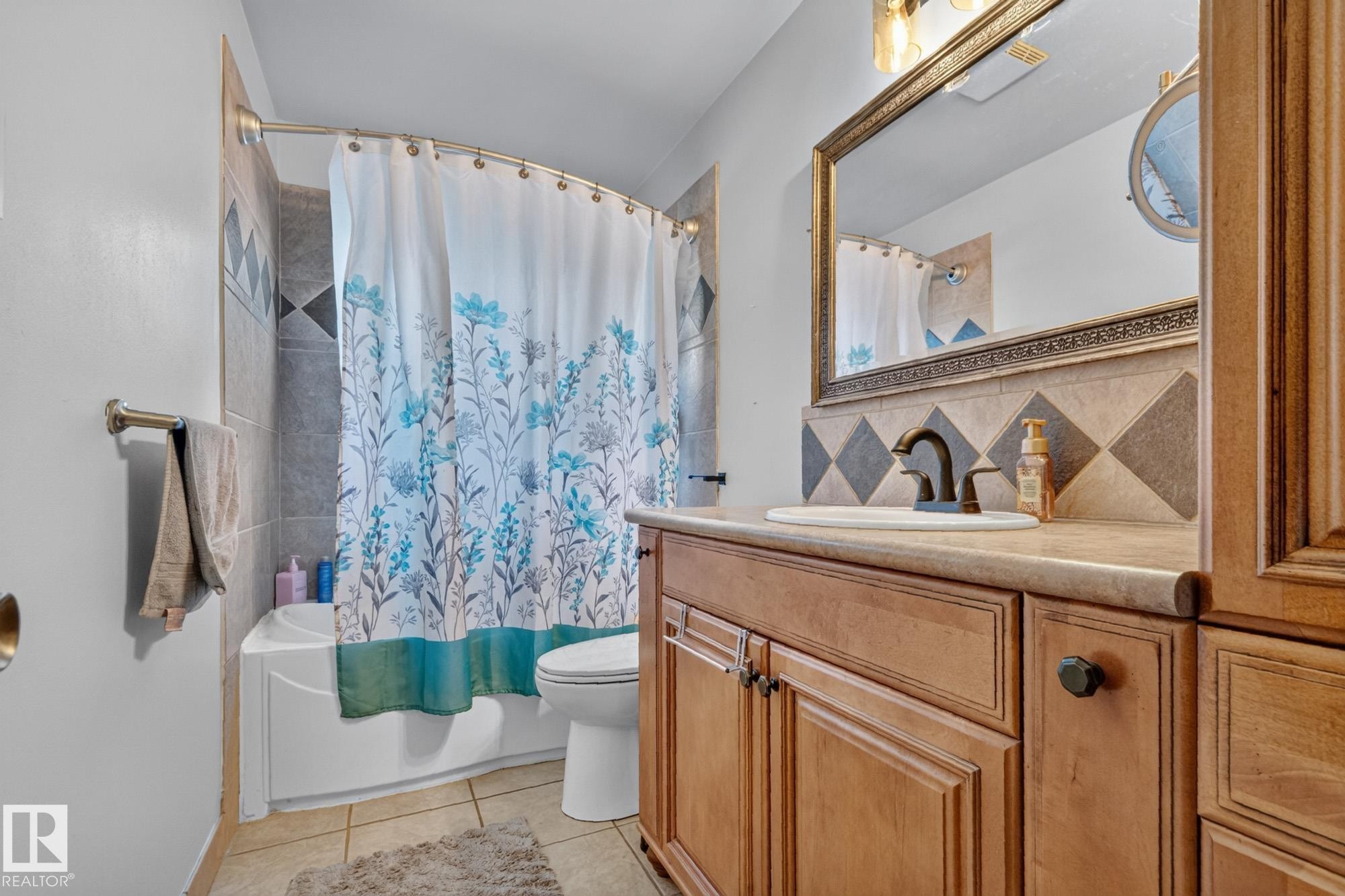 Bathroom featuring a vanity with a recessed sink, a framed mirror, and a combination tub/shower with tiled surround - 5307 104 Avenue Nw, Edmonton, AB - Indoor Photo Showing Bathroom