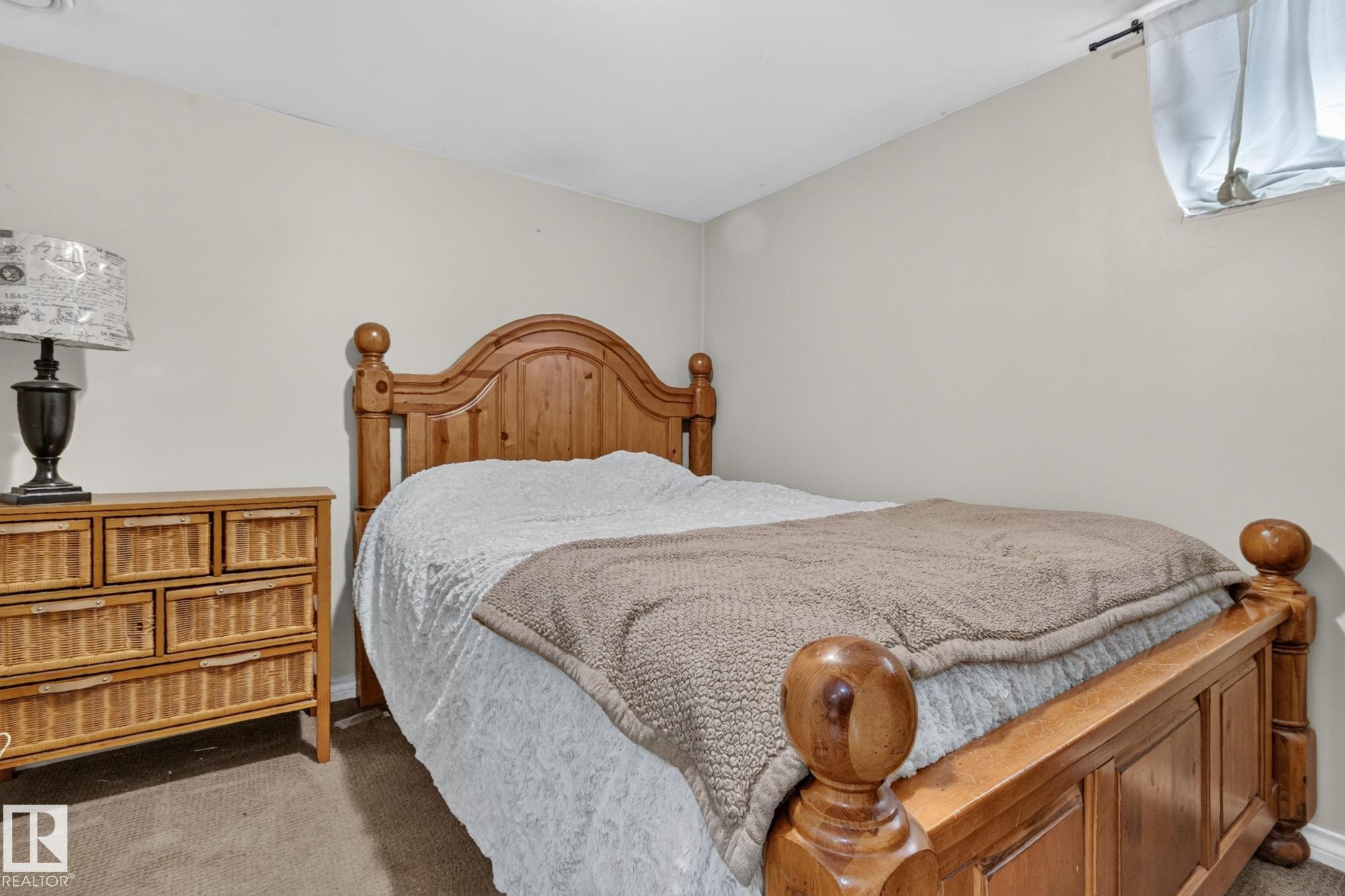 Neutral wall tones with a wood-finish bed frame and coordinating dresser - 5307 104 Avenue Nw, Edmonton, AB - Indoor Photo Showing Bedroom