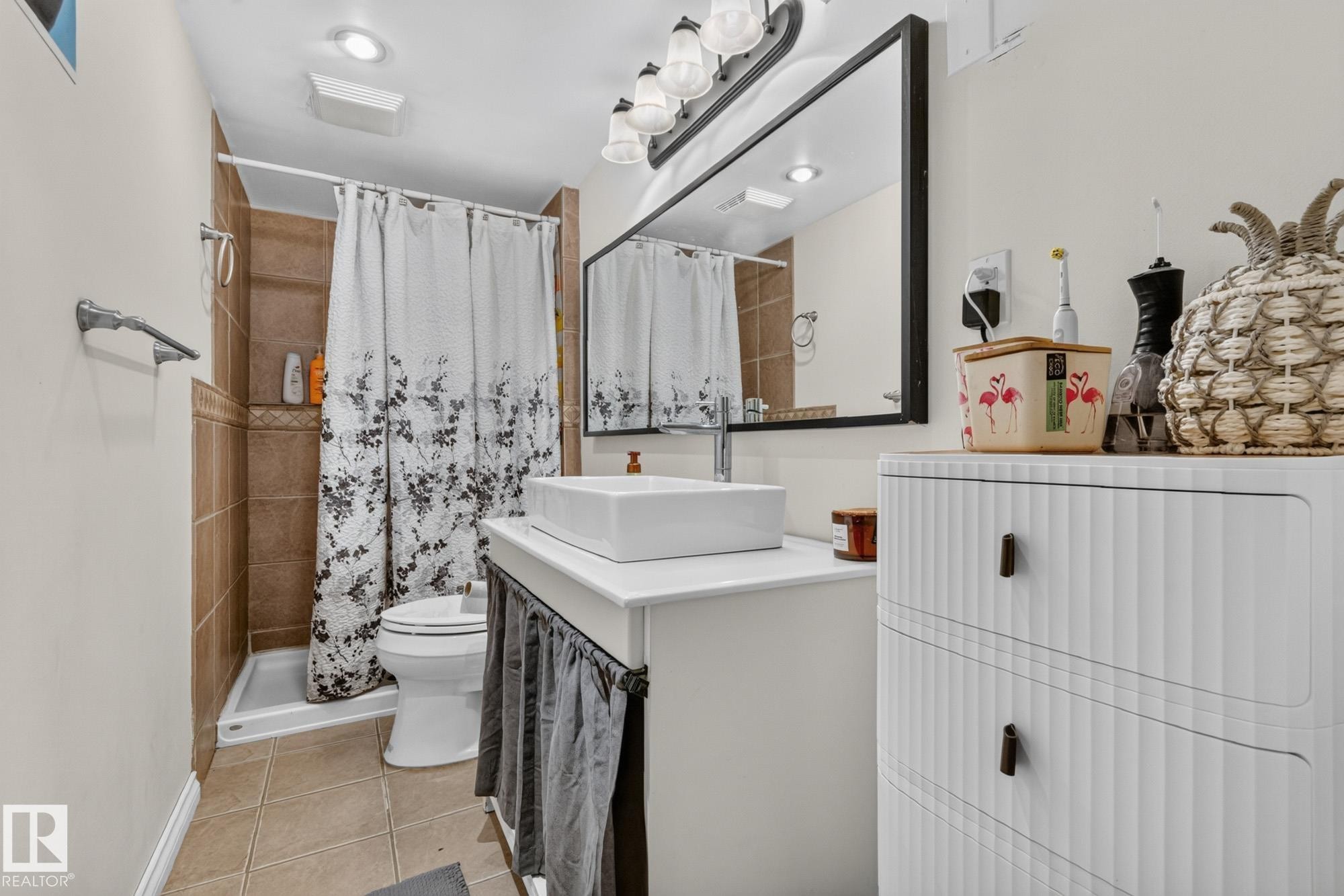 Bathroom featuring a vessel sink, dark framed mirror, and a shower with brown tile surround - 5307 104 Avenue Nw, Edmonton, AB - Indoor Photo Showing Bathroom