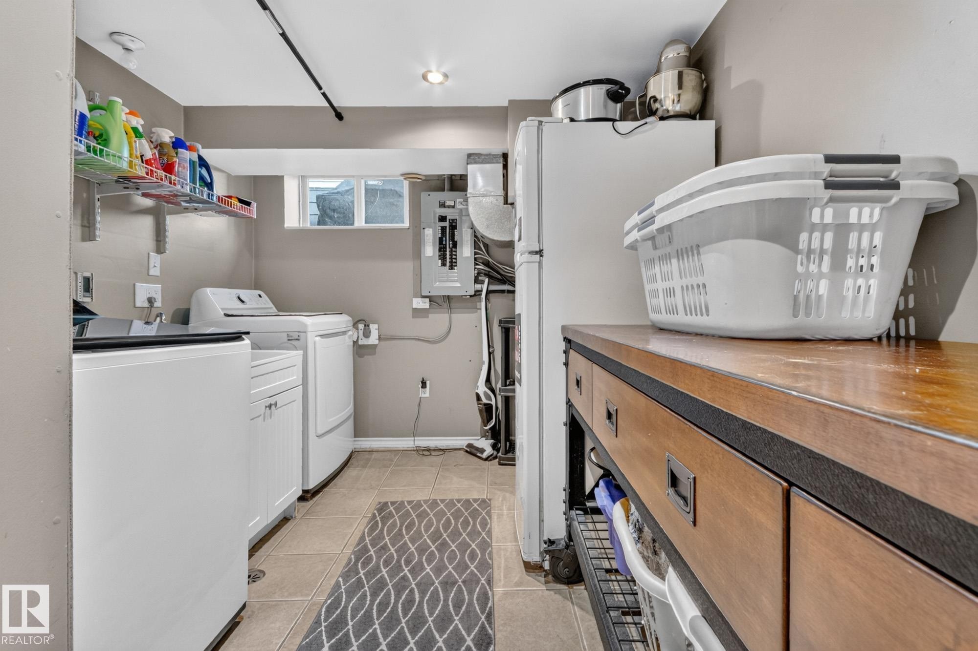 Dedicated utility space featuring a wood-finish countertop, integrated cabinetry, and ceramic tile flooring - 5307 104 Avenue Nw, Edmonton, AB - Indoor Photo Showing Laundry Room