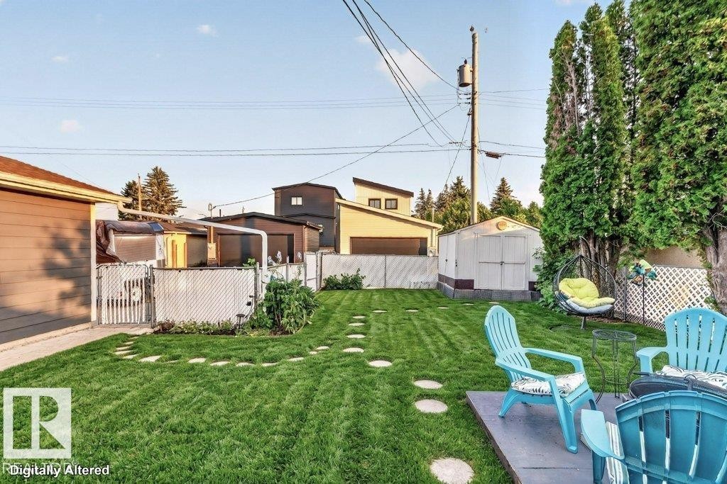 Expansive fenced backyard featuring a manicured lawn, stone paver pathway, and mature privacy trees - 5307 104 Avenue Nw, Edmonton, AB - Outdoor