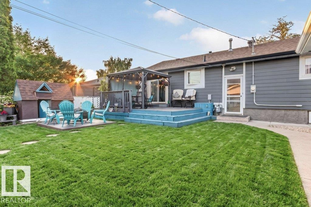 Expansive backyard featuring a manicured lawn, a raised wood deck with built-in gazebo, and a separate patio area - 5307 104 Avenue Nw, Edmonton, AB - Outdoor