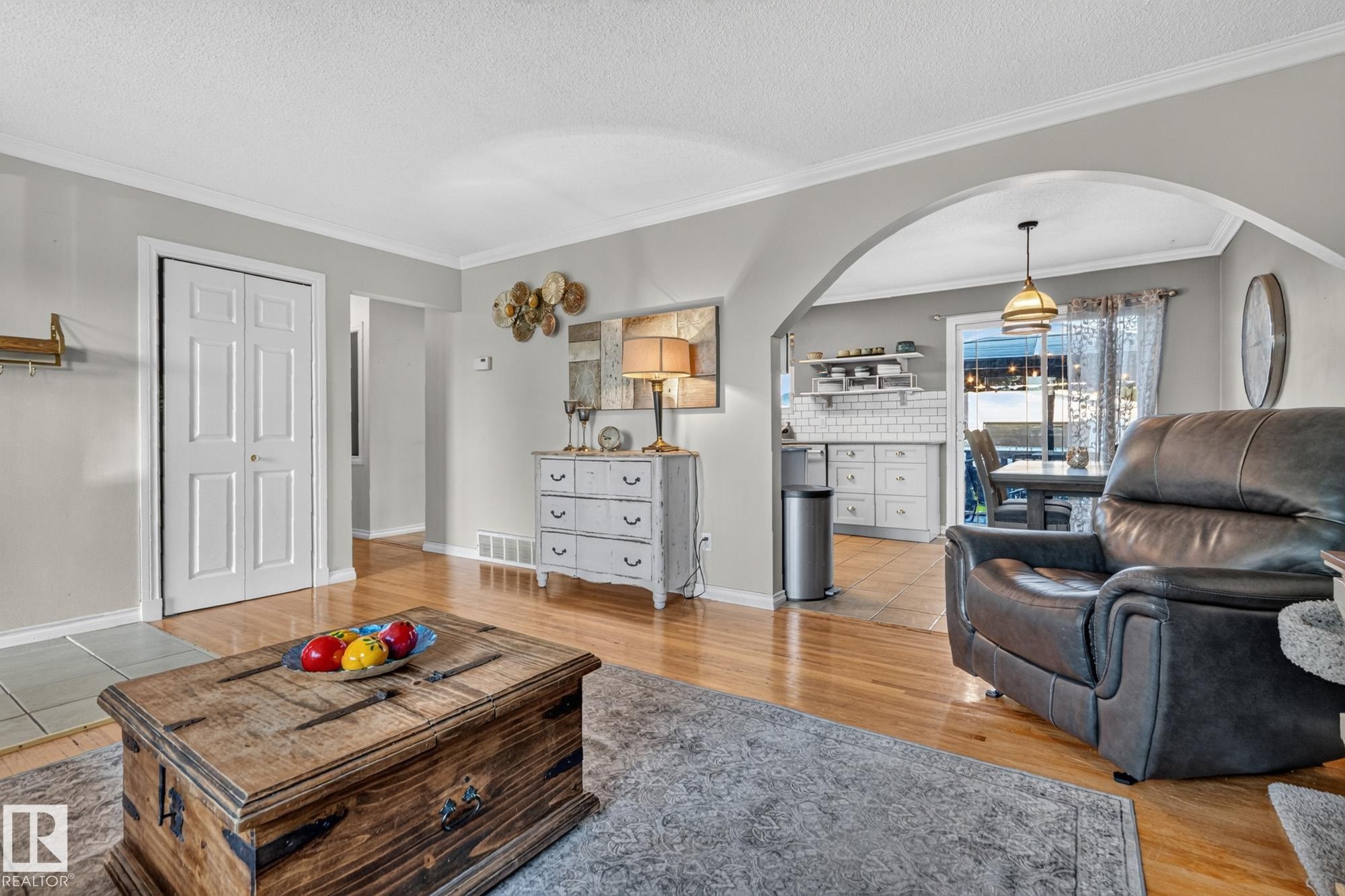 Bright living area featuring wood-finish flooring, light gray walls, and crown molding - 5307 104 Avenue Nw, Edmonton, AB - Indoor Photo Showing Living Room