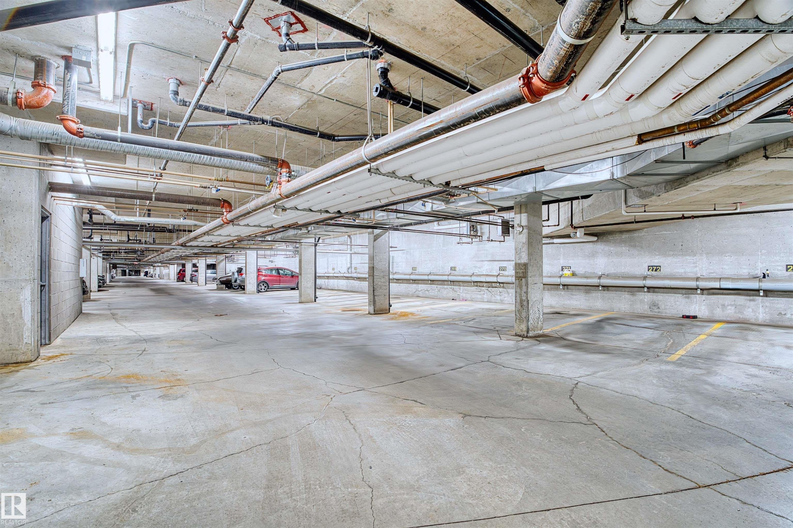 Underground parking facility featuring concrete flooring and structural columns - #317 3719 Whitelaw Ln Nw, Edmonton, AB - Indoor Photo Showing Garage