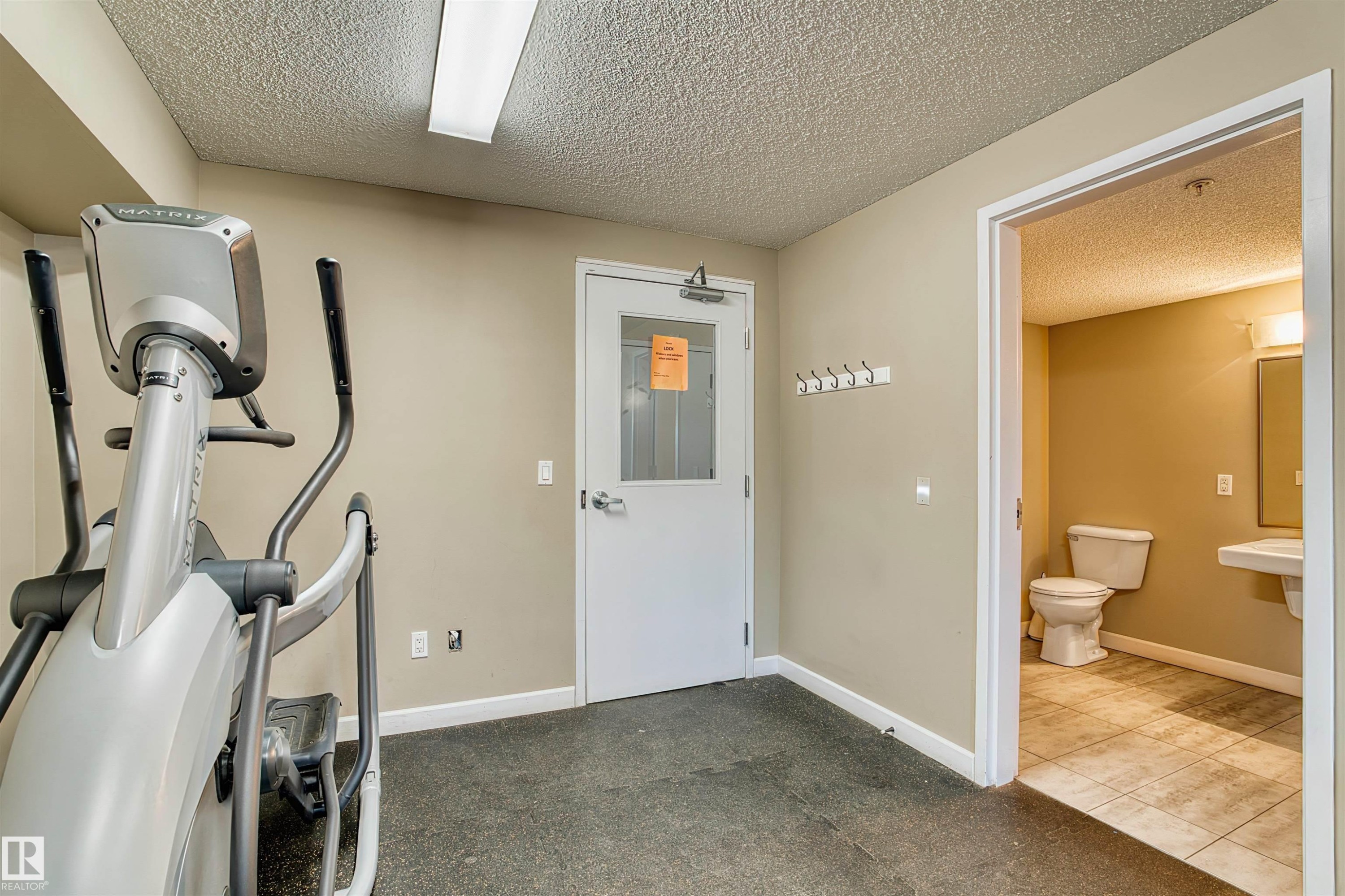 Dedicated fitness area featuring rubberized flooring and neutral-toned walls - #317 3719 Whitelaw Ln Nw, Edmonton, AB - Indoor Photo Showing Gym Room