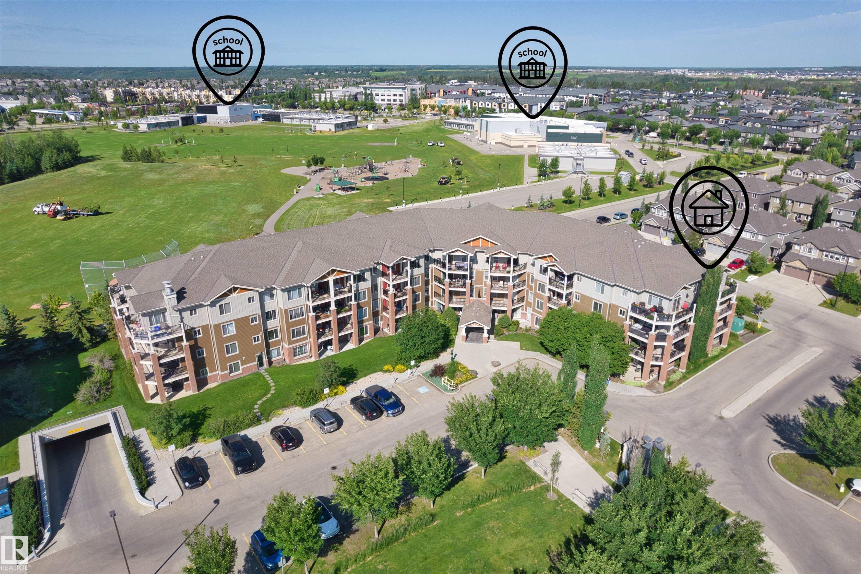 Contemporary multi-story condominium building featuring a mixed-material facade, private balconies, an underground parking entrance, and surface parking - #317 3719 Whitelaw Ln Nw, Edmonton, AB - Outdoor With View